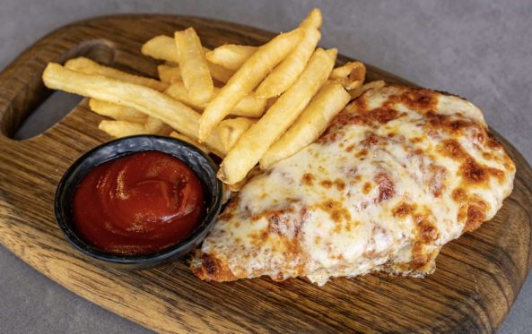 Kids chicken parmigiana with fries and tomato sauce on a board